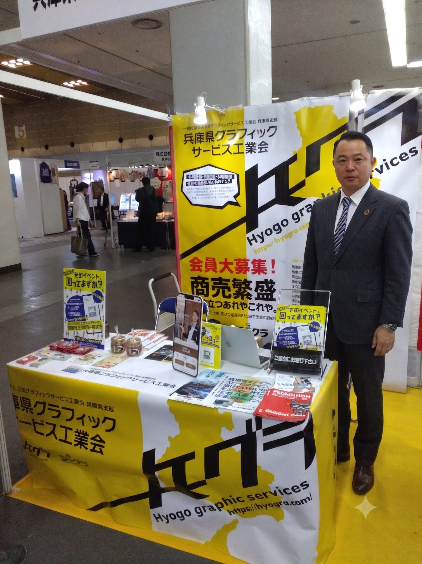 兵庫県グラフィックサービス工業会（ヒョウグラ）ブースに立つ富士高速印刷